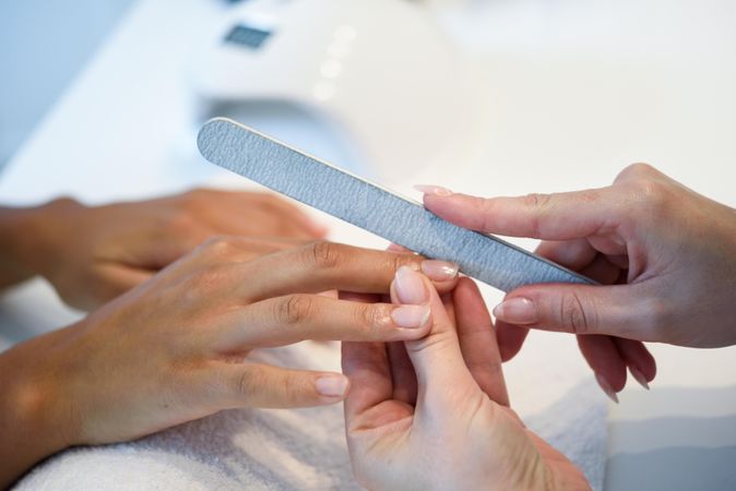 Beautician filing nails of a customer