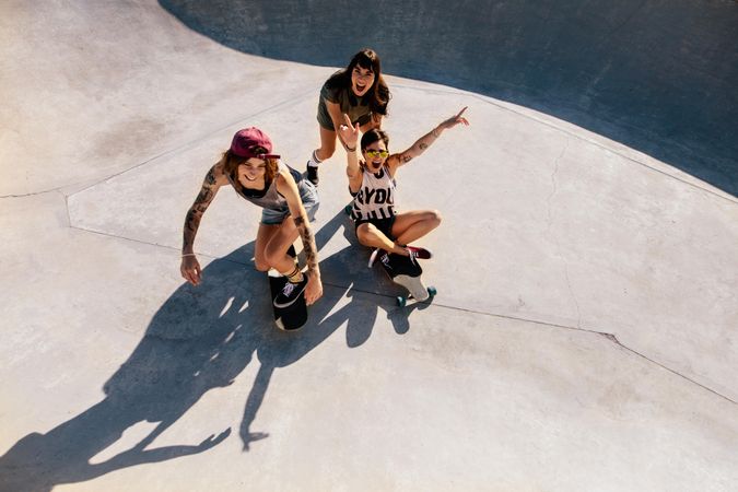 Top view of three young women laughing and having fun at skate park