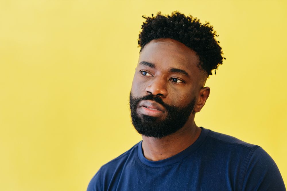 Portrait of contemplative Black man in navy t-shirt in yellow studio