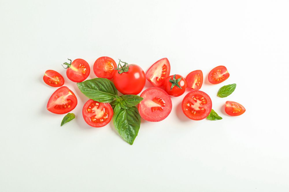Flat lay composition with fresh cherry tomatoes and basil on blank background, space for text. Ripe vegetables
