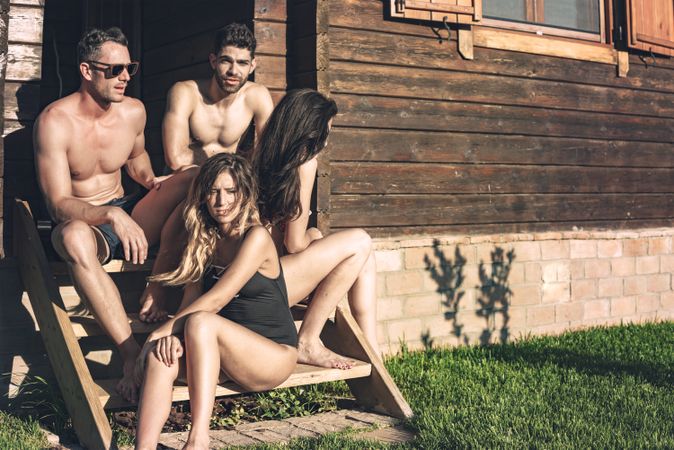 Four friends sitting on stairs on sunshine