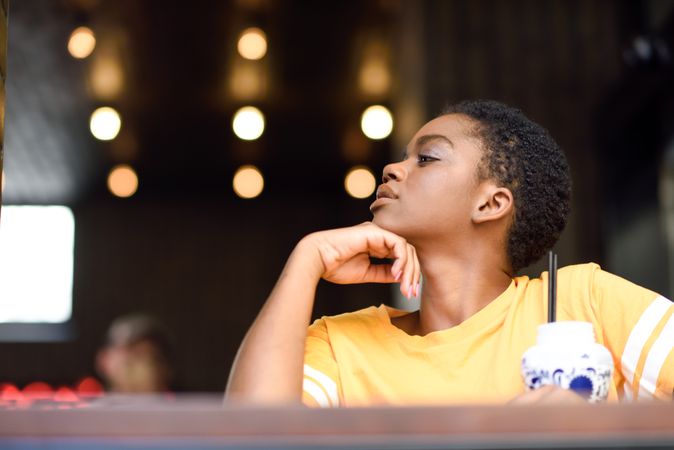 Female sitting at counter of modern cafe looking to the side