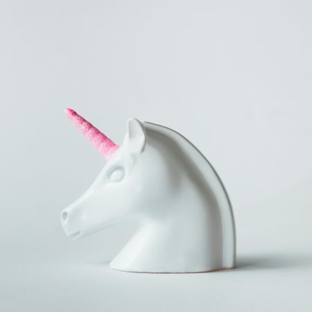 Profile of painted unicorn head with pink horn on bright background