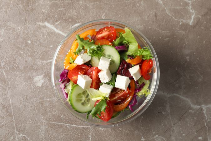 Glass bowl with fresh salad on grey background, copy space