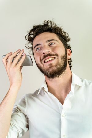 Happy young man listening to a voice message on his smartphone.