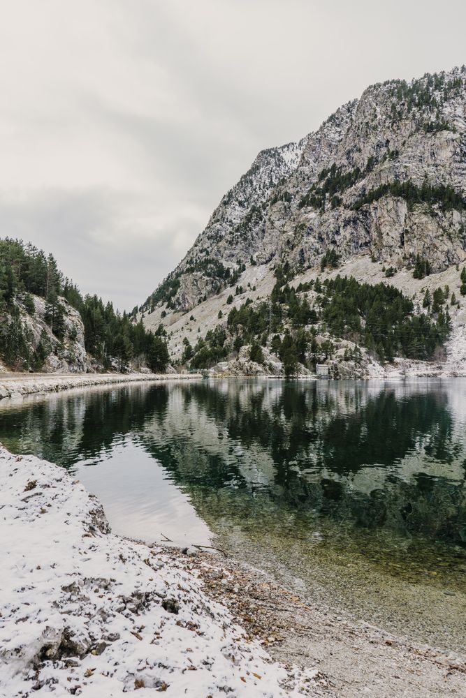 Wonderful lake between hills in snow and cloudy sky