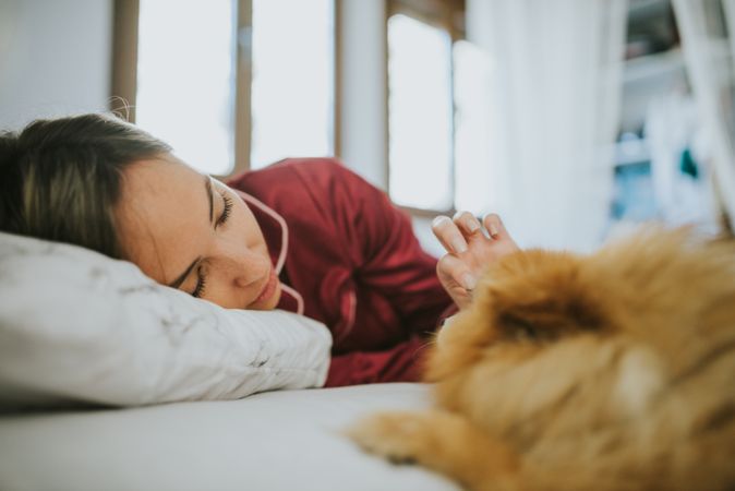 Smiling woman lying in bed with dog