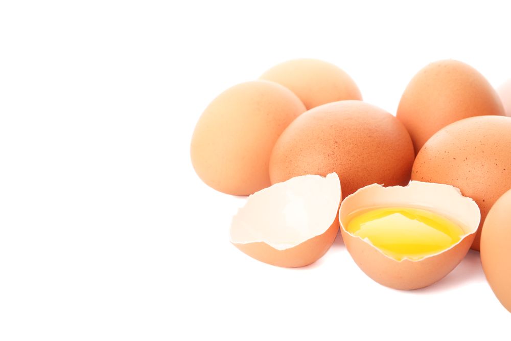 Chicken eggs and half yolk isolated on light background