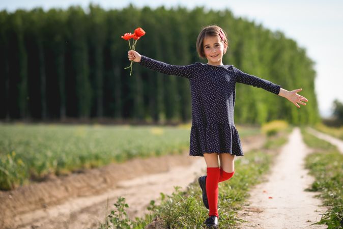 Smiling girl with red flowers in her hand