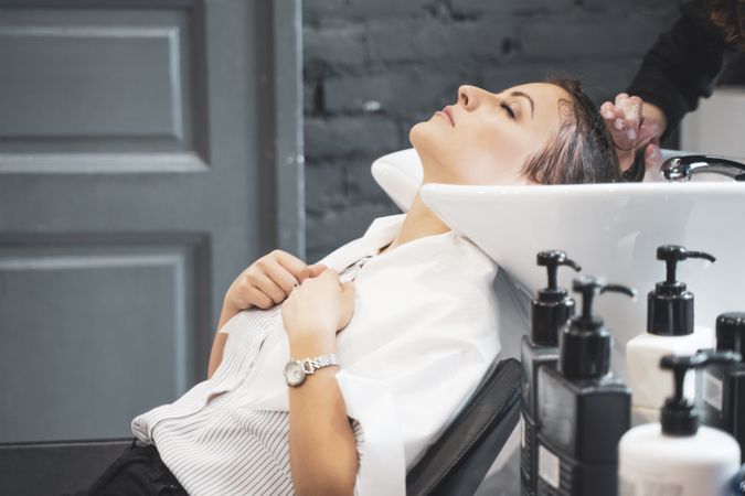 Stylist washing hair of female client