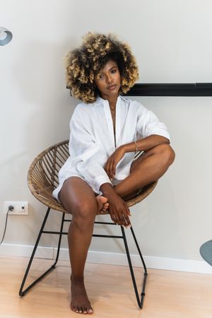 Black woman sitting in round chair in light room