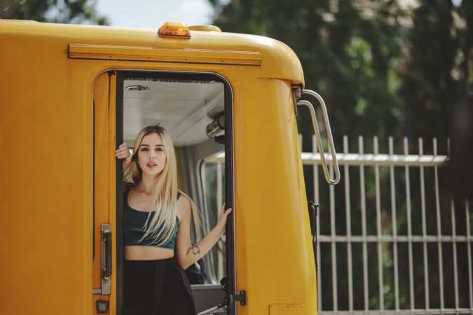 Cheerful blonde woman standing on train in drivers cabin