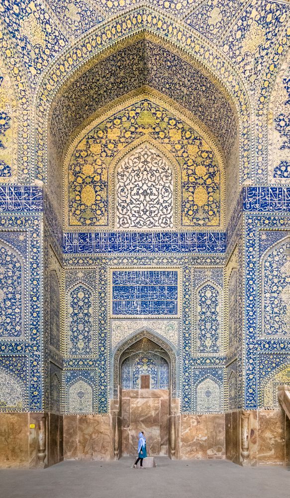 Woman standing in mosque with colorful tiles on dome