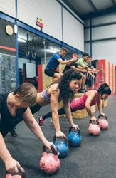 Sportswomen doing push-ups with kettlebells
