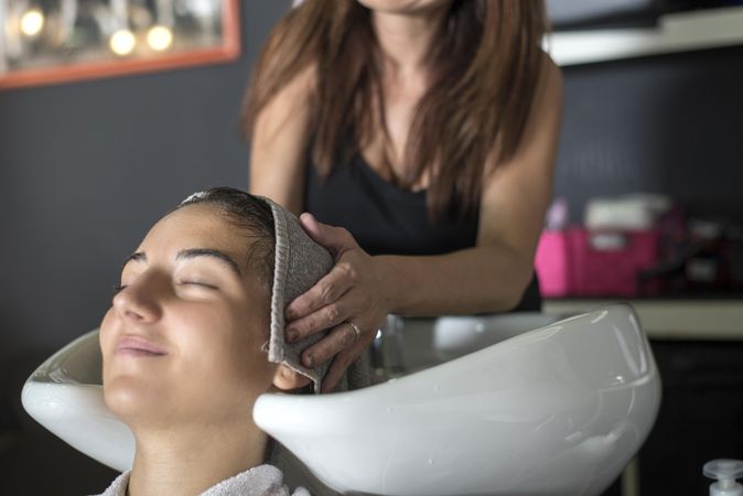 Hair stylist drying hair of woman with small towel