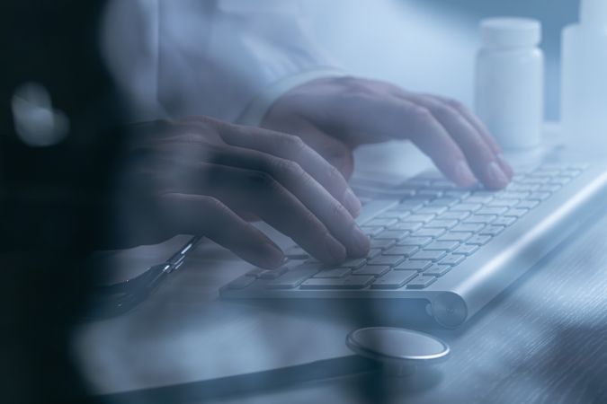 Doctor working at computer keyboard through X-ray film
