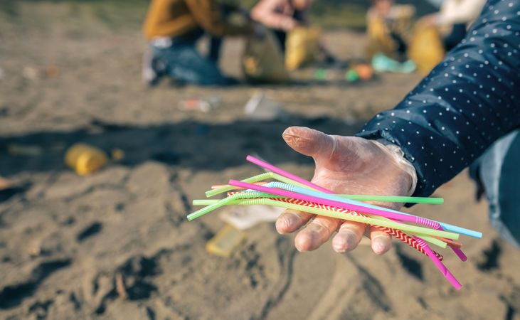 Woman showing handful of straws collected on the beach