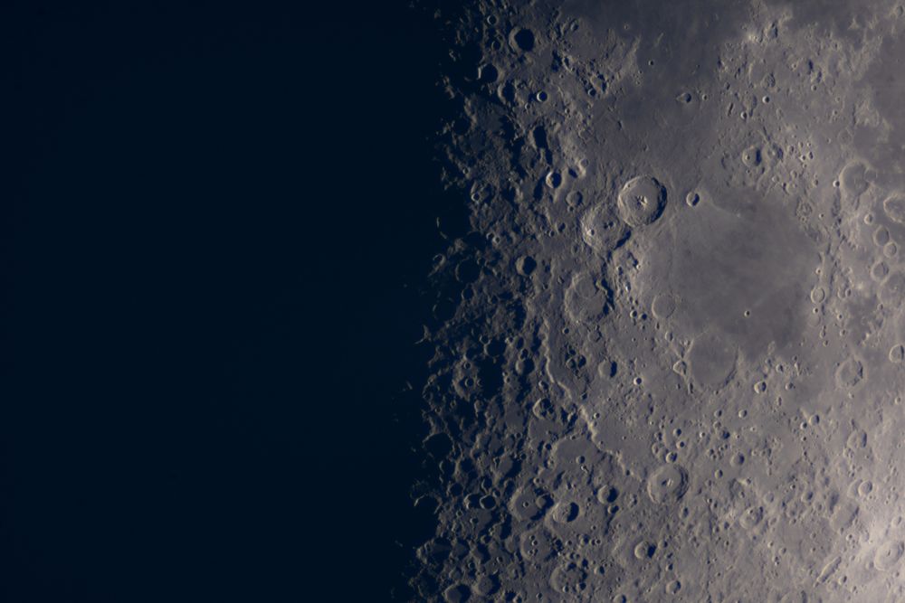 View of moon’s craters illuminated along lunar terminator line.