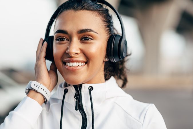 Happy woman in exercise gear listening to music on headphones