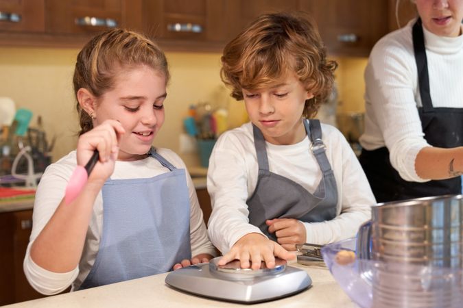 Cute kids playing on kitchen during baking with mother
