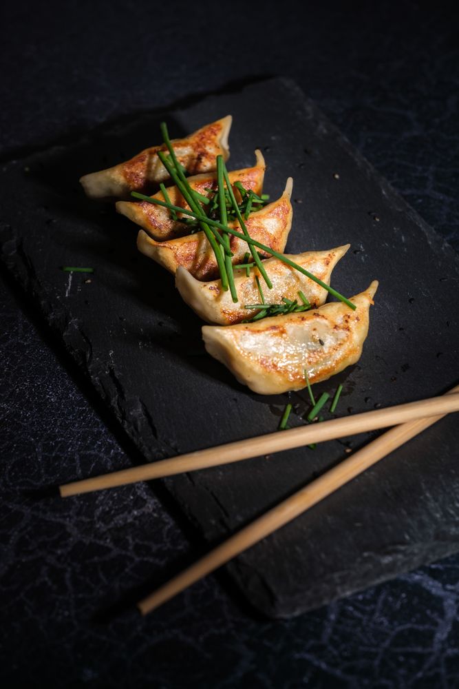 Fried Japanese dumplings with green onion on slate board