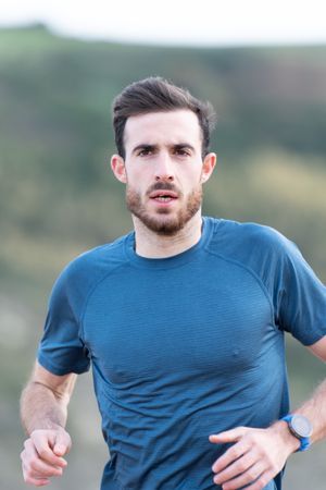 Sportsman in active wear jogging on lonely beach