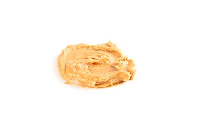 Creamy peanut butter isolated on bright background. A traditional product of American cuisine