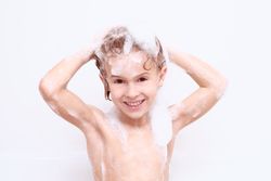 Smiling boy washing hair in bathroom
