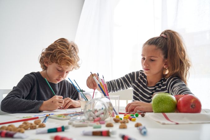 Children painting at table with cookies and apples