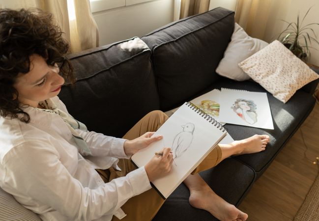 Woman writing on paper on sofa in room