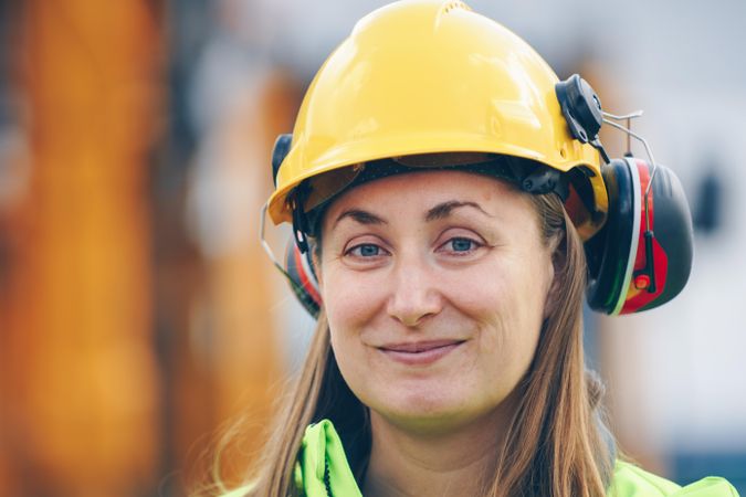 Woman in yellow helmet smiling at work