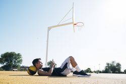 Male basketball player using his smartphone resting after training