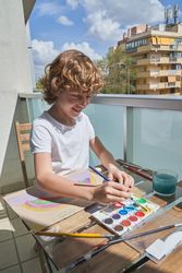 Cheerful boy painting on terrace