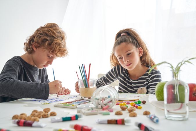 Concentrated siblings painting together at table