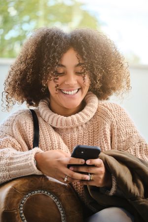 Cheerful Black woman using smartphone