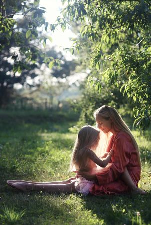 Little girl sitting on her mother's lap out in nature