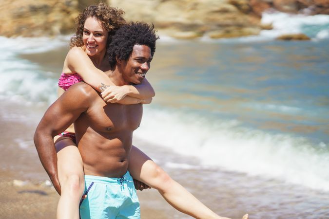 Happy multiethnic couple having fun on sandy beach