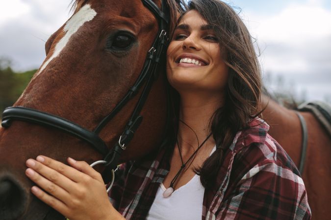 Close up of happy young woman hugging her horse