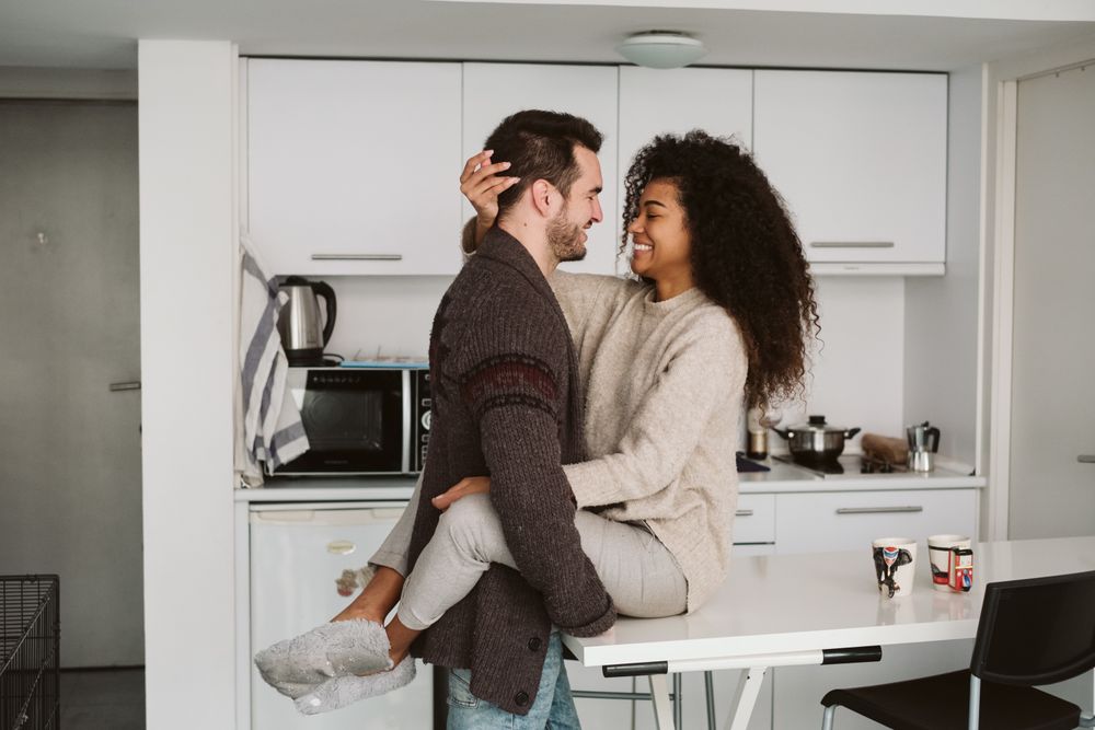 Cheerful multiracial couple hugging in kitchen