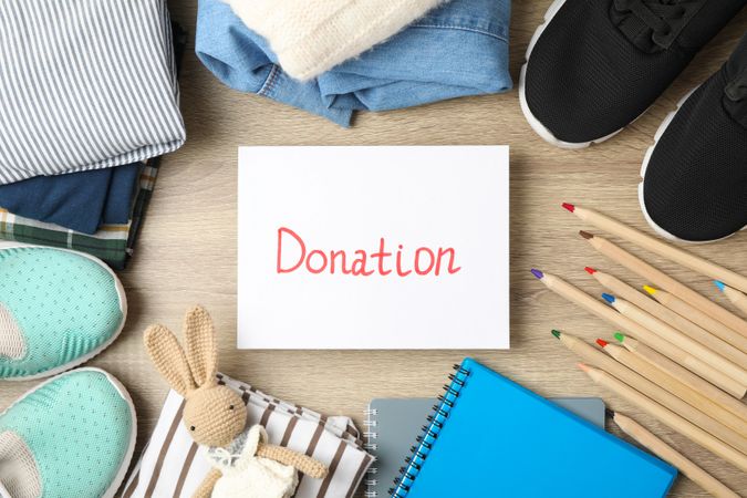 Text Donation, clothes and different accessories on wooden background, top view
