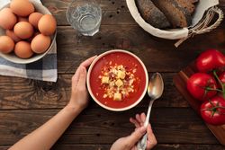 Person hands holding bowl with gazpacho
