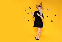 Concept of Halloween, young woman on yellow background