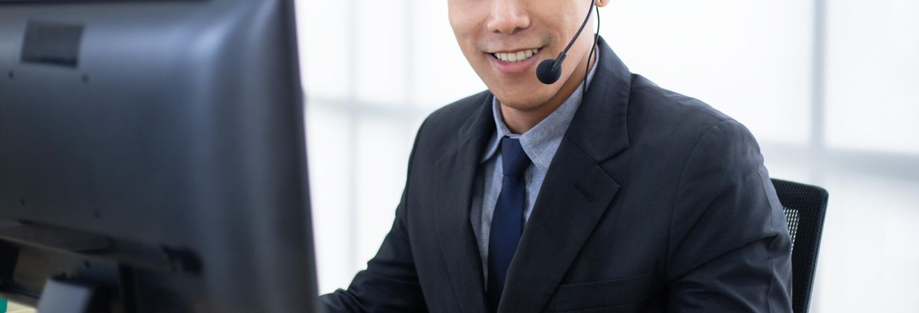 Banner of man smiling at computer wearing headset