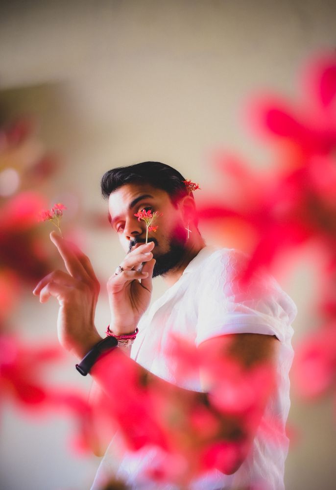 Portrait of bearded man with red flowers against light background