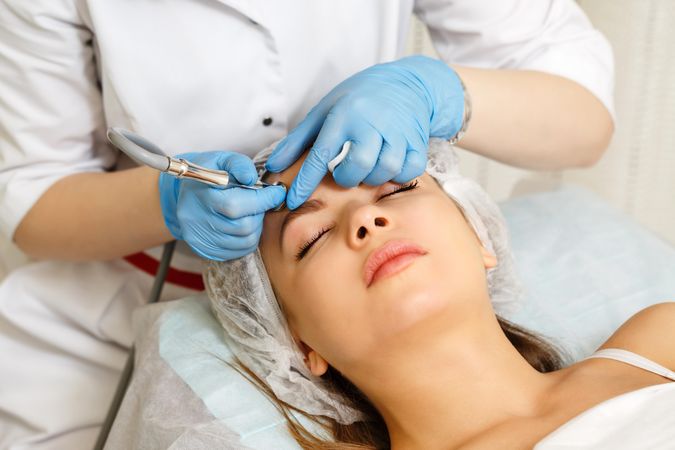 Woman having facial beauty treatment with instrument on her forehead