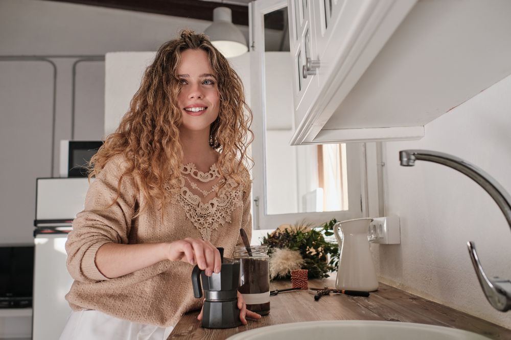 Young housewife preparing coffee in kitchen
