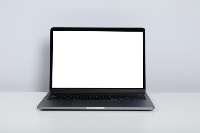 Opened silver laptop with blank screen and keyboard on desk with copy space