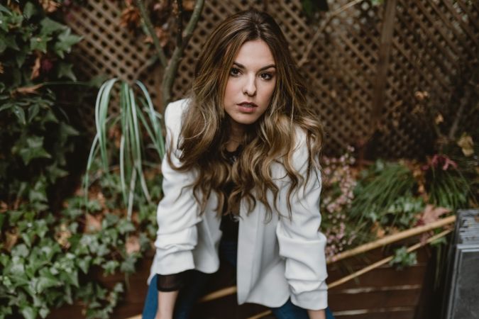 Woman sitting on planter in garden