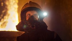 Portrait of fireman with helmet and raging fire behind