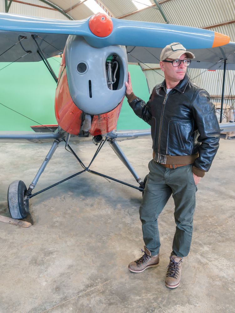 Confident pilot beside retro plane in hangar